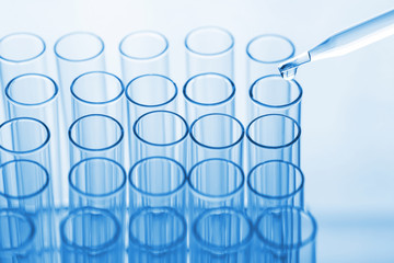 science pipette with a drop of substance over laboratory test tu