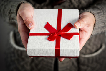 Female hands holding a gift box with red ribbon. Close Up.

