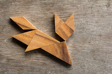 Wooden tangram as running cat shape on old wood background