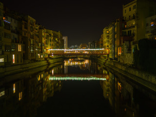 Fototapeta na wymiar Puente reflejado sobre el río Oñar, con luces nocturnas decorativas de Navidad en Girona, Cataluña, España, en Diciembre de 2016