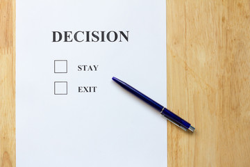 Decision paper with stay and exit choice on wood background