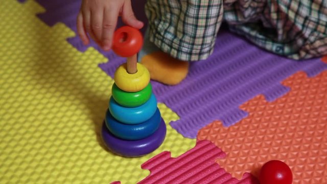 Bambino gioca con numero otto, con una piramide, con un gioco d'incastro