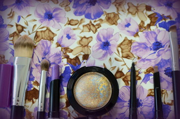 Косметика для макияжа с тенями для век и кистями на синем фоне с узором  - женская косметичка 