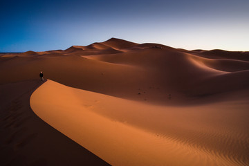 Fototapeta na wymiar woman at Sunrise at the Dunes of Hassi Labiad, Morocco