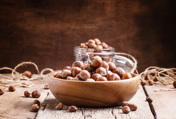 Raw hazelnuts in shell in a bowl on the old wooden background, s
