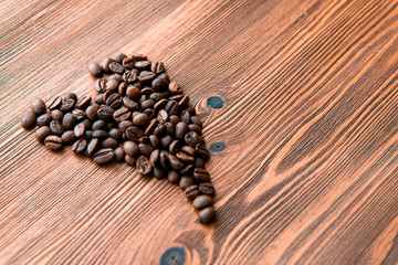 Heart symbol, roasted coffee beans in rustic wooden background.