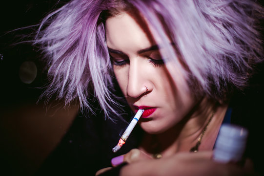 Portrait of a girl with a cigarette. young beautiful girl hipster smoking a cigarette in the street under the snow. her hands lights a lighter, lighting a cigarette tobacco