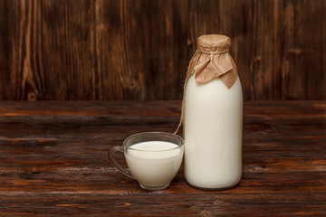 Bottle of milk and cup on rustic wooden table