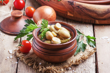 Homemade pickled mushrooms champignons in earthenware bowl on th