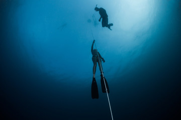 Free diver ascending along the rope in the depth