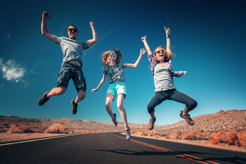 Three young friends jumping and having fun on the empty asphalt road