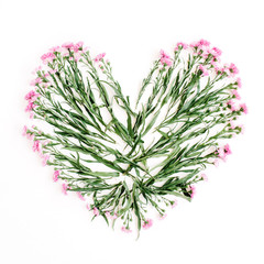 Heart symbol made of pink wildflowers. Flat lay, top view. Valentine's background.