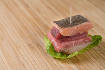 Small meat sandwich (fish, beef, pork, chicken) on a cutting board. 