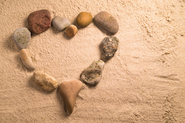 Fototapeta na wymiar Heart arranged with stones on the sand