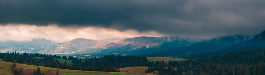 Ultra-wide panorama of Carpathian mountains. Dramatic stormy clouds over mountain range. Ukraine.