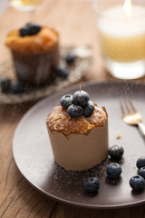 Blueberry muffin in a dish decorated with fresh blueberry and white candle on the table
