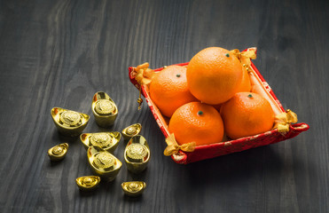 Chinese New year,gold ingots and oranges on brown wood table top