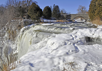Fototapeta na wymiar running stream of water at the edge of Webster Falls during Winter near Hamilton Dundas Ontario Canada