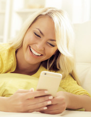 Happy blonde girl with a smartphone at home