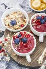 Healthy breakfast. Blueberry banana smoothie in a la carte dishes with granola and pomegranate on  marble background. selective focus