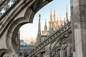 Details of marble spiers and statues of Milan Cathedral, Italy, at sunset.