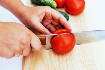 Sliced tomatoes and cucumbers on wooden board.