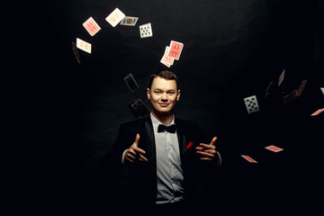 Closeup of man magician with two playing cards in his hand over grey background - obrazy, fototapety, plakaty