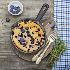 Home comfort food. Fresh blueberry pie in a cast iron frying pan on  wooden background. Top view