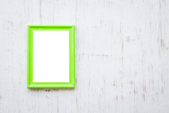 Green photo frame over white rustic wooden background