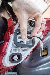 A hand checking the cable connector of a modern car taillight