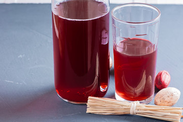 Fresh pomegranate and pomegranate juice in a transparent glass with decor nutmeg and dried herbs on a dark background