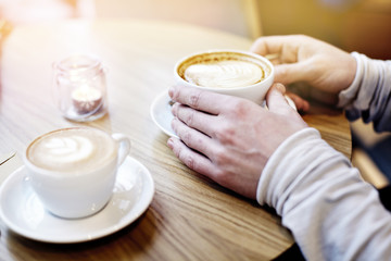 Two coffee cups in man handson table in modern cafe. St. Valentines celebration concept. Date and love in restaurant.