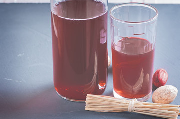 Fresh pomegranate and pomegranate juice in a transparent glass with decor nutmeg and dried herbs on a dark background