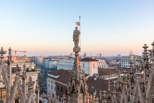 Details of marble spiers and statues of Milan Cathedral, Italy, at sunset.