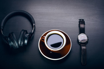 Cup of coffee on a dark table. Concept of business. Laptop, headphones, watch.