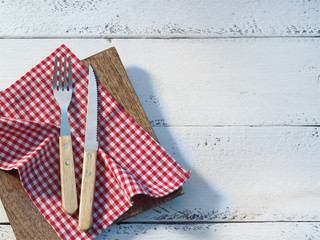 Besteck mit rotweißem Tuch auf weißem Holz 