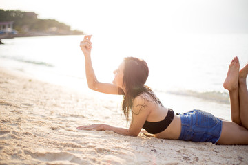 Pretty woman is laying down on the beach with sunset