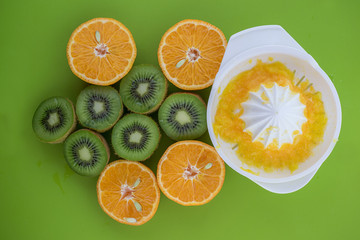 Oranges and kiwis cutted on half on green surface