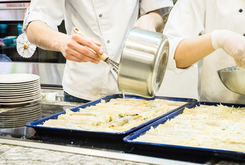 Cooking lasagna. The cook pours sauce. Italian Cuisine.