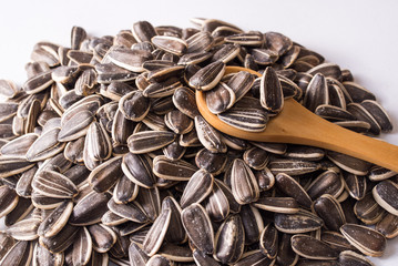 Sunflower seeds and a wooden spoon on a white background