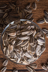 a bowl of sunflower seeds on a wooden background. Top view