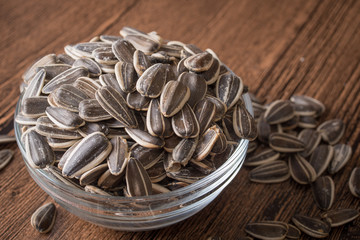 a bowl of sunflower seeds on a wooden background