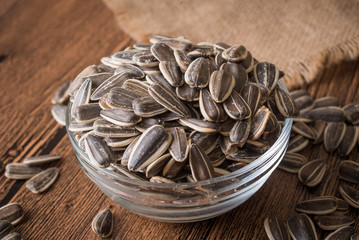 a bowl of sunflower seeds on a wooden background