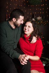 Fototapeta premium Romantic couple sitting and hugging in christmas decorated home interior. Christmas time.