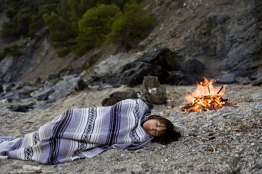 femme qui campe dehors en dormant à la belle étoile au coin du feu