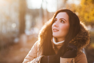 winter outdoor portrait of Girl cute funny positive. Sunny day. Portrait of an attractive brunette in the street. Skin Care, Lip care, care of the eyelashes in the winter season.

