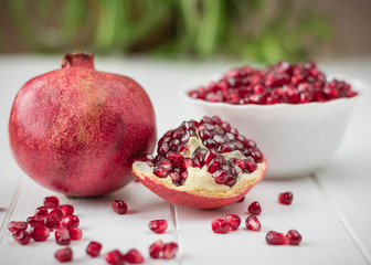 Ripe pomegranate seeds on a white wooden table. Fruit diet. Healthy lifestyle.