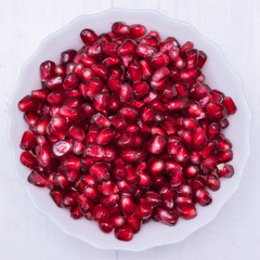 Ripe pomegranate seeds on a white wooden table. Fruit diet. Healthy lifestyle.