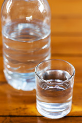Drinking water in glass and plastic bottles on a wooden table.
