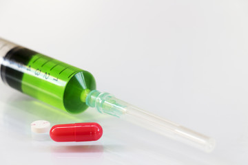 Pills and syringes for treating patients on a white background.